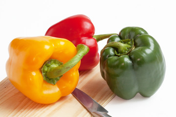 Poivrons de couleurs différentes alignés sur fond blanc 