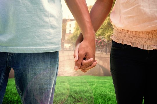 Composite image of young couple holding hands in the park