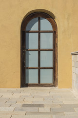 wood arched window with rough plaster wall