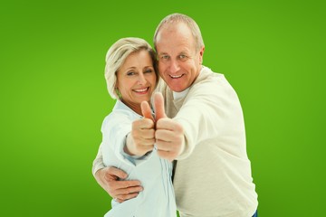 Composite image of happy mature couple showing thumbs up