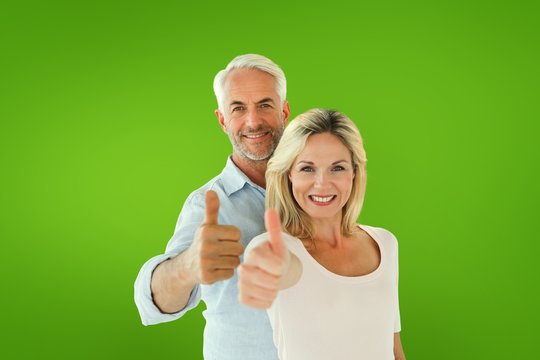 Composite image of smiling couple showing thumbs up together