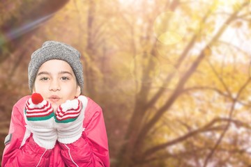 Composite image of wrapped up little girl blowing over hands