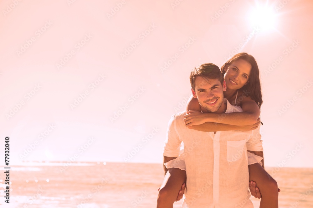 Poster smiling man giving girlfriend a piggy back looking at camera