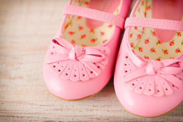 Detail of a pink girl shoes over wooden deck floor.