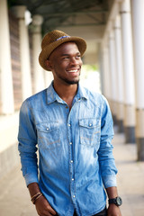 Trendy young man walking outside with hat