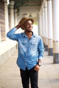 Happy young african american man walking with hat
