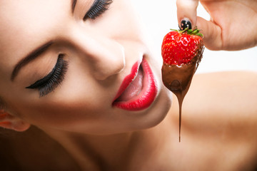 Seduction - red female lips eating chocolate strawberries - 77934037