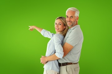 Composite image of happy couple smiling at camera and pointing