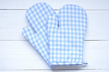 Two oven gloves on an old white wooden table