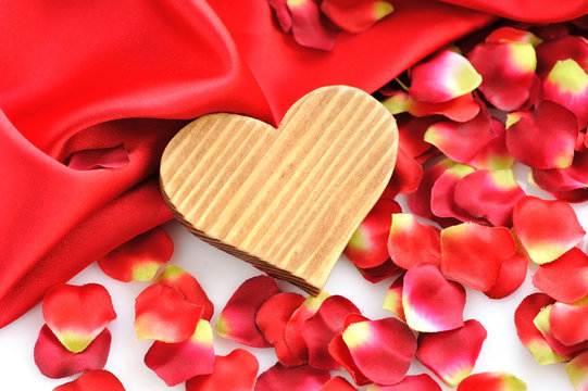 Wooden Heart on a background of red petals and satin