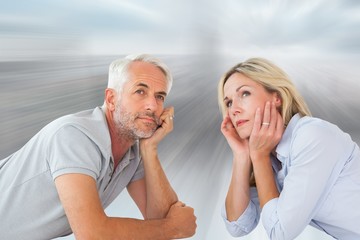 Composite image of thoughtful couple lying and looking up