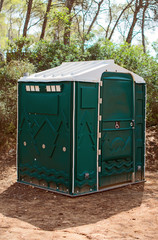 Green plastic toilet booth in the forest.