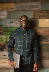 Confident young businessman smiling against wooden wall