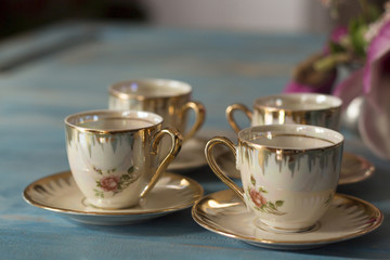 Vintage tea cups with saucers on old wooden table.