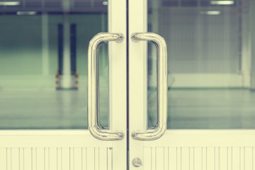 Naklejka premium Door handle part of aluminium door at interior office, factory. Modern style design with long metal steel rod, chrome or stainless steel for access room by holding, pull, sliding, open or close door.