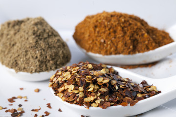 Dried red chilli flakes with other spices in white spoon