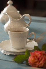 Pretty coffee cup, creamer, sugar bowl on old wooden table.