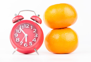 Red alarm clock and orange fruits show food and healthy time