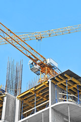 Crane and building construction site against blue sky