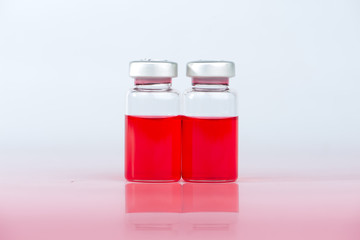 Red liquid in injection vial and shadow effect on red floor
