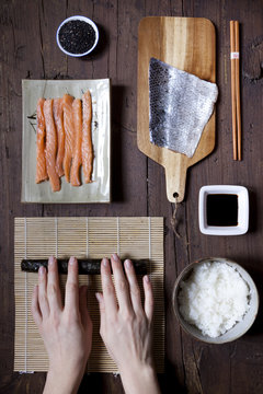overhead shot of hands rolling sushi and ingredients on table