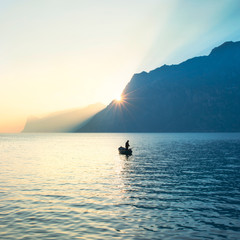 fisherman fishing in the lake under amazing sunset