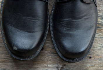 A pair of black shoes close up on wood background.