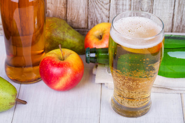 Glass and bottles of cider with fruits