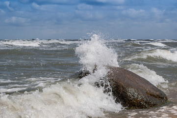 Ostseewellen brechen sich an einem Stein auf Rügen