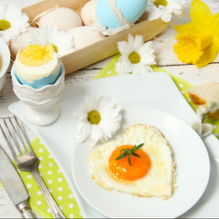 Easter table setting with flowers and eggs on old wooden table
