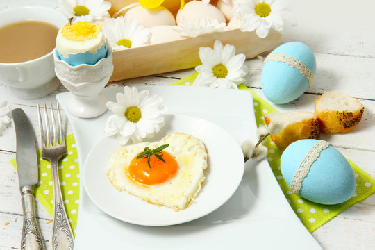 Easter table setting with flowers and eggs on old wooden table