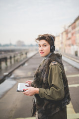 Fototapeta premium Portrait of young woman listening to music on digital tablet outdoors