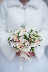 Winter wedding bouquet in hands of the bride closeup