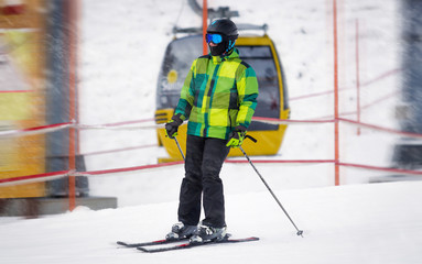 male skier riding down the slope at snowstorm