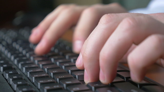 4k - Close-up of a young man hands typing on a laptop keyboard