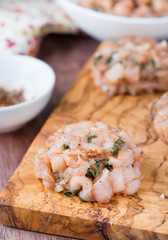 Raw chicken cutlets with herbs on olive wood background