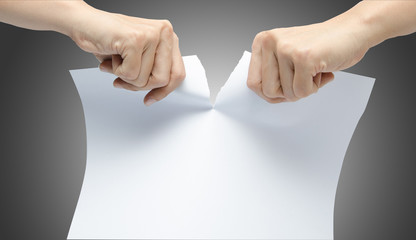 Woman hand ripping white paper on gray background