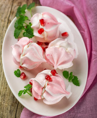 Meringue cookies in bowl with cream and pomegranate seeds