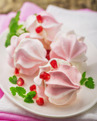 Meringue cookies in bowl with cream and pomegranate seeds