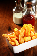 French Fries on Wooden table with Ketchup and Salt