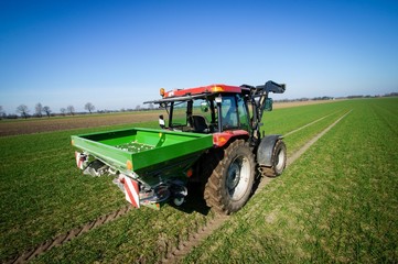 Ackerbau, Traktor mit Düngerstreuer bei der Frühjahrsdüngung