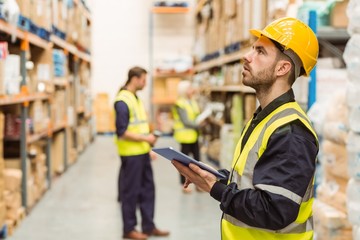 Focused warehouse manager writing on clipboard