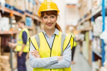 Warehouse manager smiling at camera with arms crossed