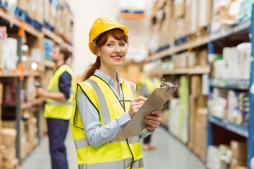 Smiling warehouse manager holding clipboard