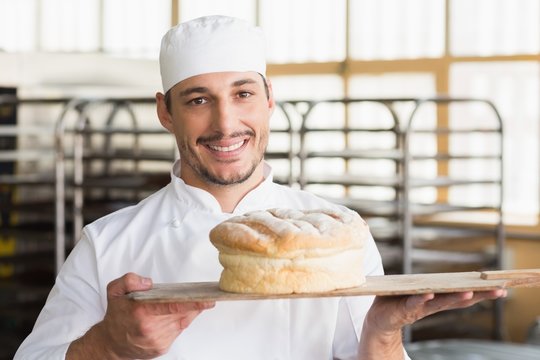 Baker showing a freshly baked loaf