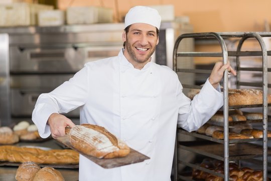 Smiling baker looking at camera holding bread