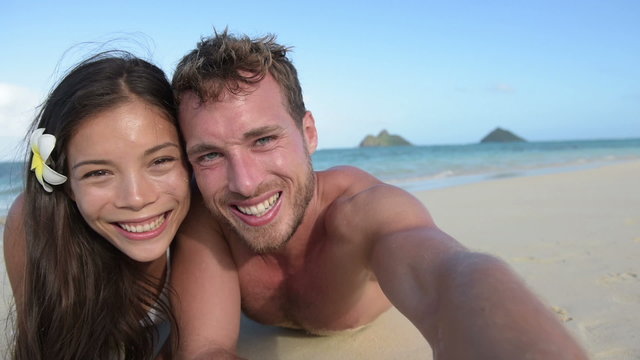 Couple relaxing on beach taking selfie picture