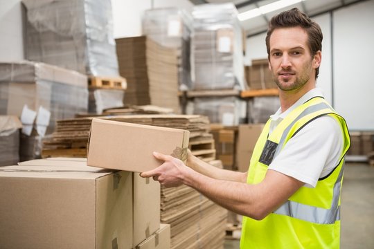 Smiling warehouse worker taking a box