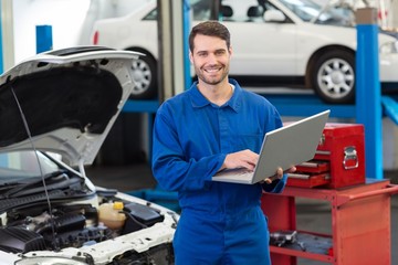 Smiling mechanic using his laptop