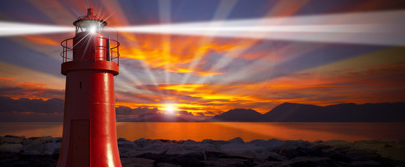 Rode vuurtoren met lichtstraal bij zonsondergang